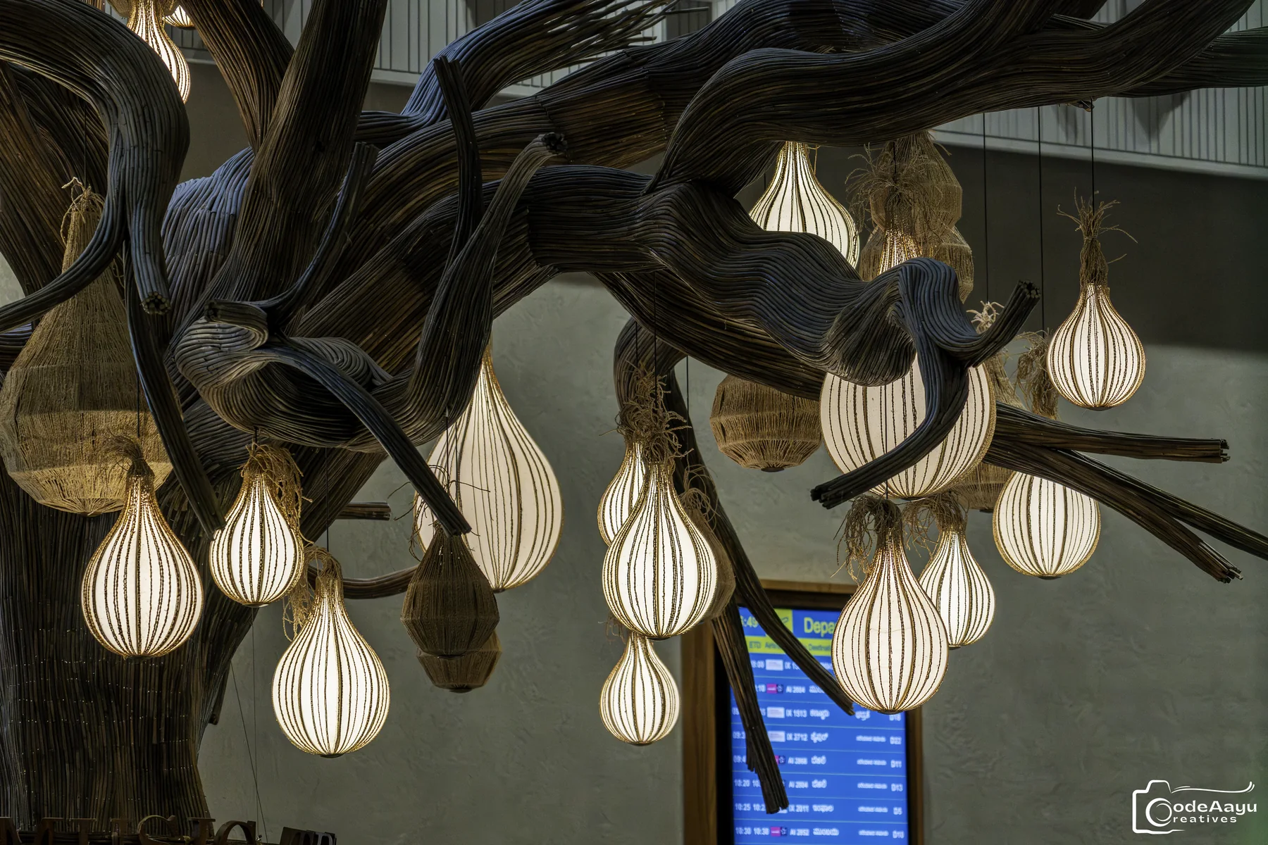 Sculptural tree installation glowing with hanging lights