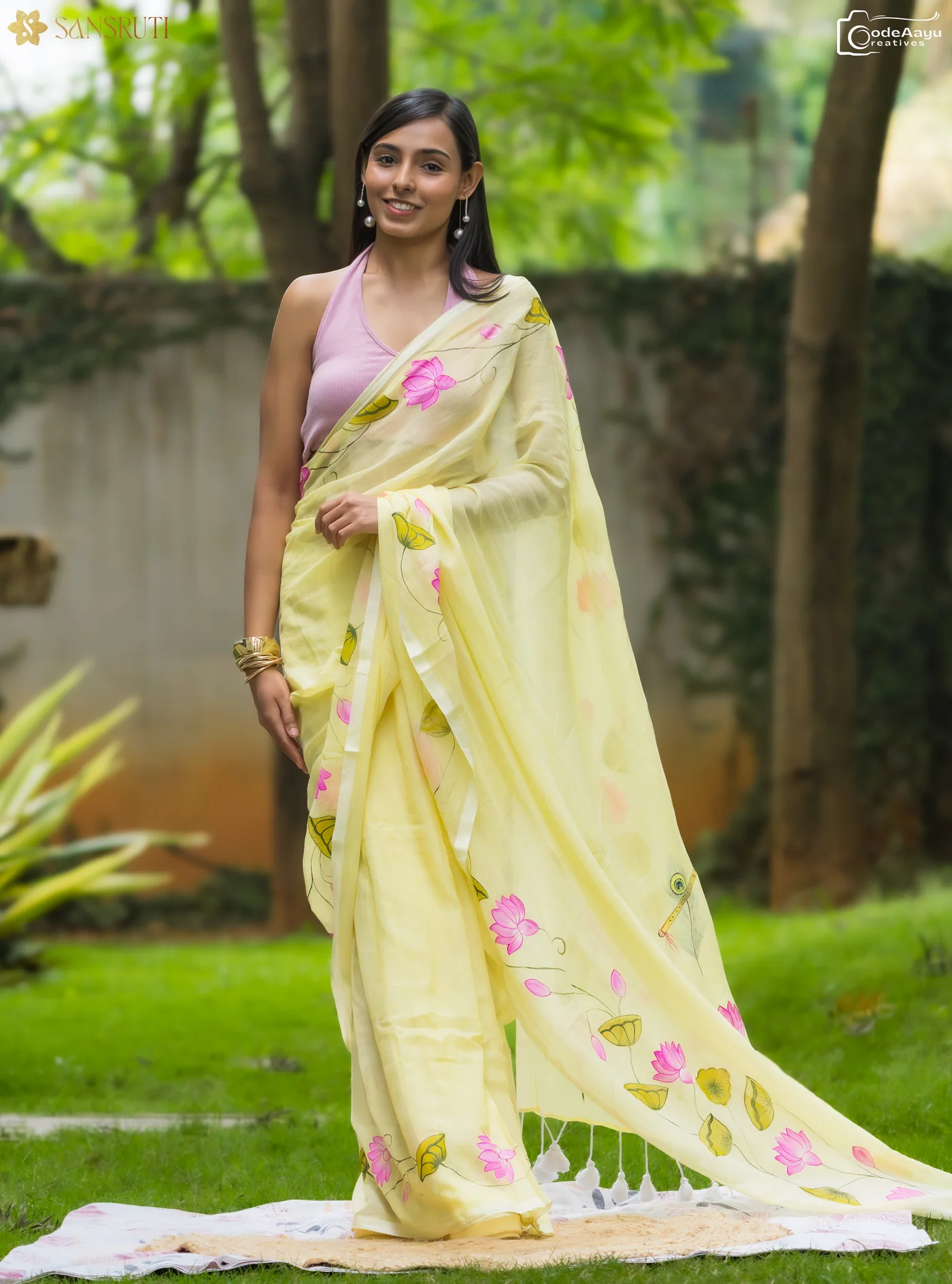 Model smiling in a yellow hand-painted saree during a brand shoot